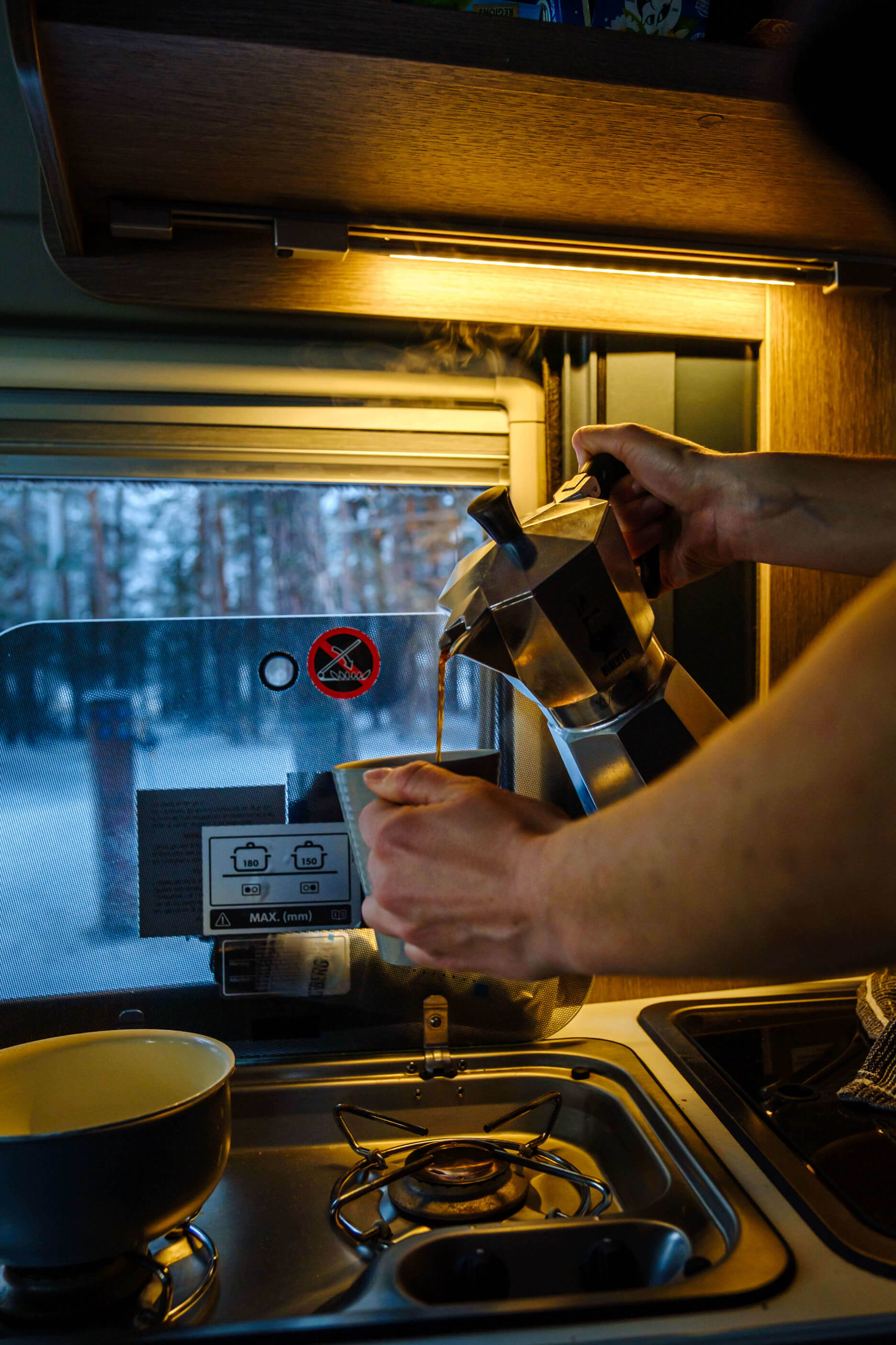 Personne se servant un café dans le confort de son van aménagé